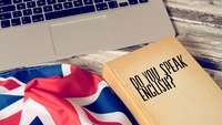 UK-Flagge und Buch liegen vor einem Laptop