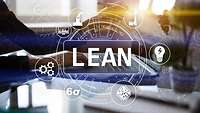 Symbole und "LEAN"-Schriftzug im Overlay über Tisch mit Laptop