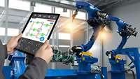 Tablet mit Schaubild wird vor Roboterarme gehalten